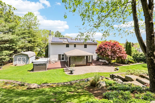 back of property with a storage unit, a deck, an outbuilding, a chimney, and a lawn