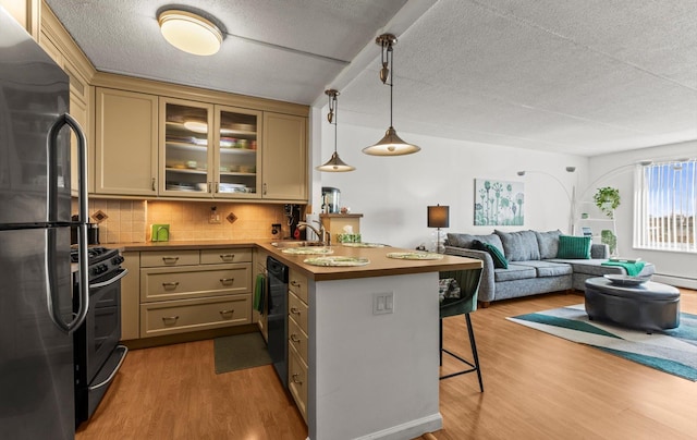 135 Post Ave Unit 5N, Westbury, NY 11590 - kitchen with a sink, a breakfast bar area, a peninsula, wood finished floors, and black appliances