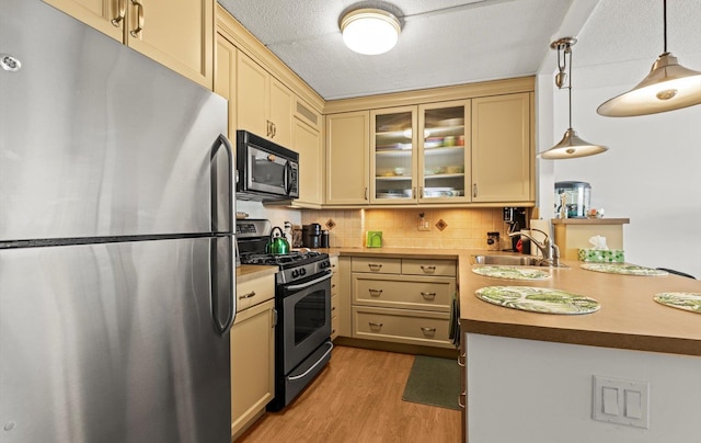 135 Post Ave Unit 5N, Westbury, NY 11590 - kitchen featuring cream cabinets, appliances with stainless steel finishes, a sink, a peninsula, and light wood-type flooring