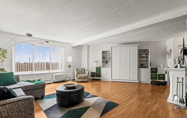 135 Post Ave Unit 5N, Westbury, NY 11590 - living room with a textured ceiling, wood finished floors, and a baseboard radiator