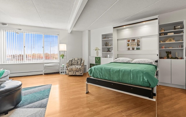 135 Post Ave Unit 5N, Westbury, NY 11590 - bedroom with beam ceiling, a textured ceiling, baseboard heating, and wood finished floors