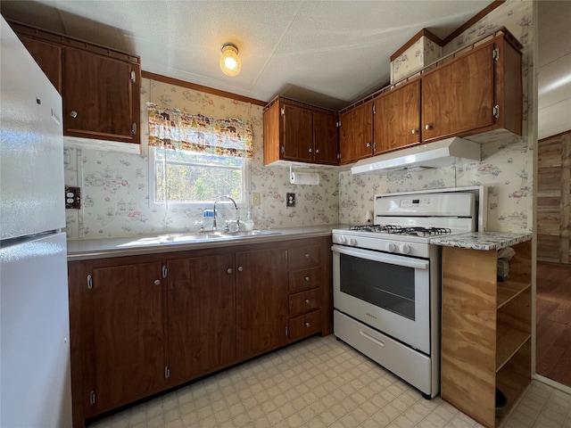 kitchen with light floors, white appliances, light countertops, and wallpapered walls