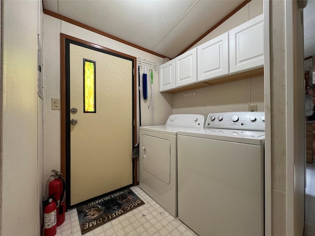 clothes washing area with washing machine and clothes dryer, light floors, and cabinet space