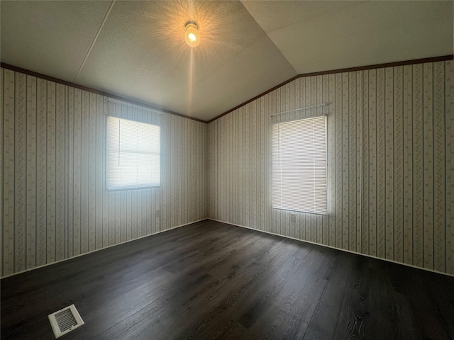 empty room with visible vents, dark wood-style flooring, and lofted ceiling
