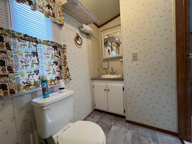 bathroom with toilet, wallpapered walls, baseboards, vanity, and lofted ceiling