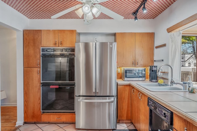 kitchen with brown cabinetry, a sink, a ceiling fan, and black appliances