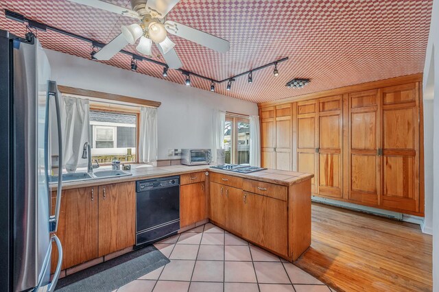 kitchen with track lighting, a peninsula, tile countertops, a ceiling fan, and appliances with stainless steel finishes