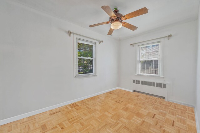 empty room with baseboards, radiator, ceiling fan, and a healthy amount of sunlight