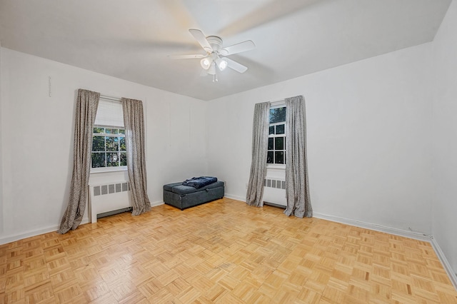unfurnished room featuring baseboards, ceiling fan, and radiator heating unit