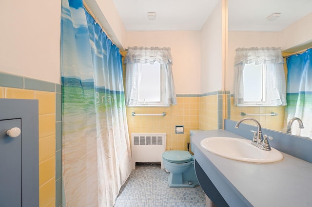 full bath featuring tile walls, a wainscoted wall, vanity, toilet, and radiator