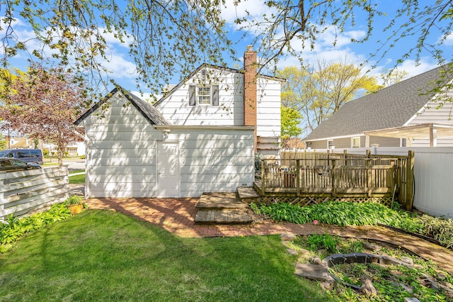 back of house featuring a lawn, fence, a chimney, and a deck