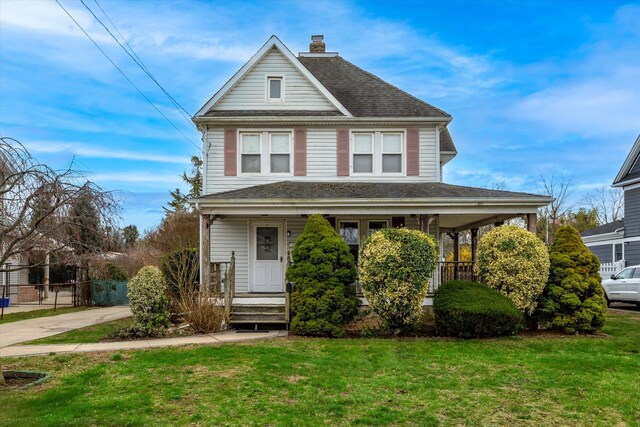 view of front facade with covered porch, fence, a chimney, and a front lawn