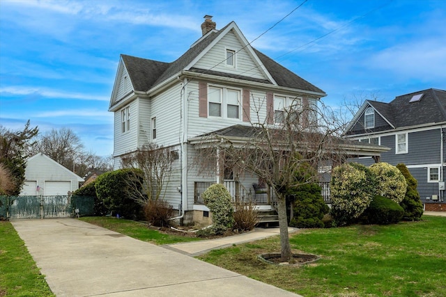 victorian home featuring a porch, a chimney, a front yard, a garage, and an outdoor structure
