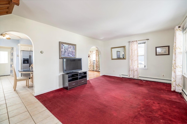 unfurnished living room featuring light colored carpet, arched walkways, baseboards, a baseboard radiator, and light tile patterned flooring