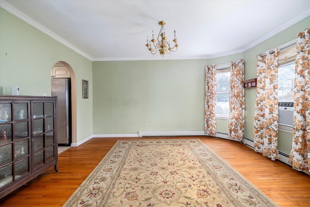 empty room featuring arched walkways, wood finished floors, baseboards, an inviting chandelier, and ornamental molding