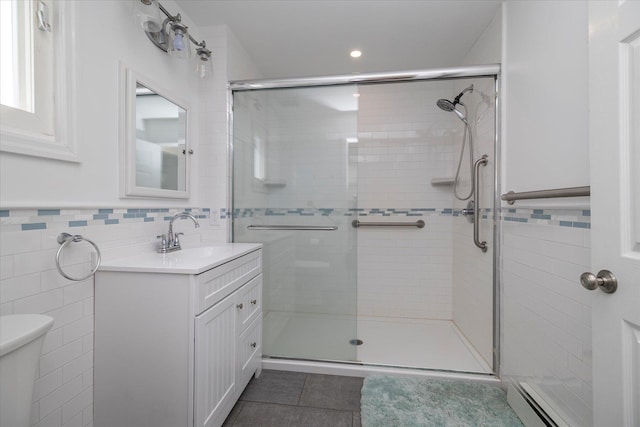 full bathroom with vanity, tile patterned floors, tile walls, a shower stall, and a baseboard radiator