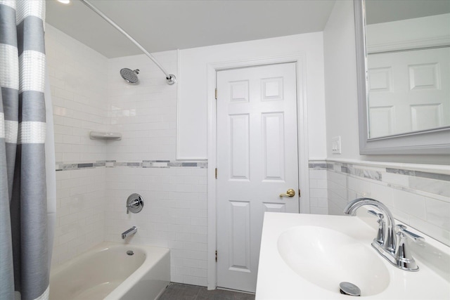 full bathroom featuring tile walls, wainscoting, a sink, and shower / tub combo