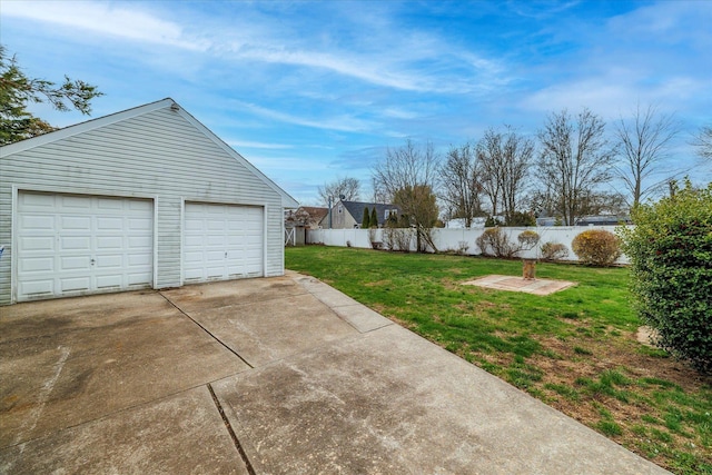 view of yard featuring fence, a detached garage, and an outbuilding