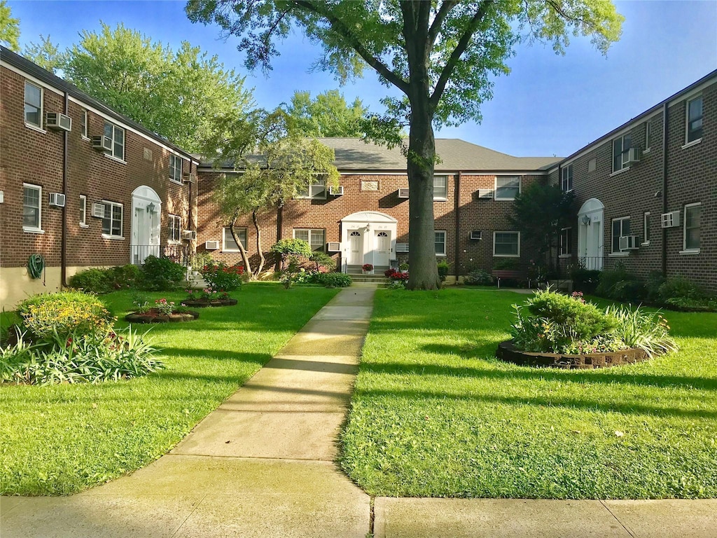 multi unit property with brick siding, a residential view, a front yard, and cooling unit
