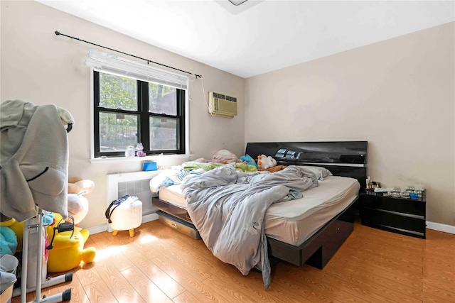 58-37 246th Cres Unit 1F, Little Neck, NY 11362 - bedroom with baseboards, a wall mounted air conditioner, and light wood-type flooring