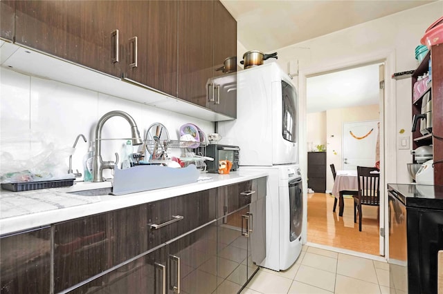 58-37 246th Cres Unit 1F, Little Neck, NY 11362 - kitchen featuring stacked washer and dryer, dark brown cabinetry, light countertops, a sink, and light tile patterned floors