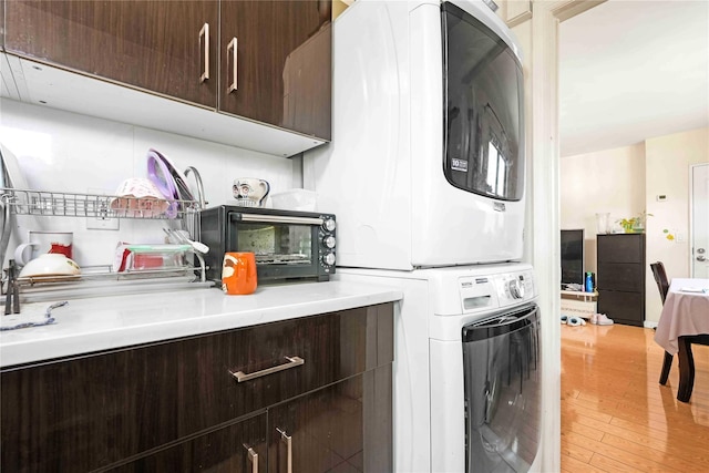 58-37 246th Cres Unit 1F, Little Neck, NY 11362 - washroom with laundry area, stacked washer and clothes dryer, light wood-style flooring, and a toaster