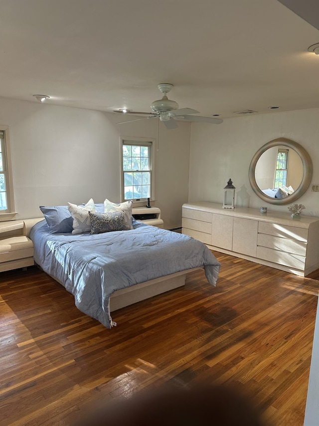 bedroom with ceiling fan, multiple windows, and wood finished floors