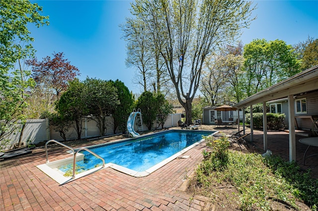 view of swimming pool with a patio, a water slide, a fenced backyard, a fenced in pool, and an outdoor structure