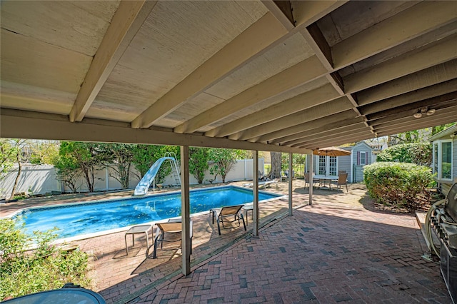 view of pool with an outbuilding, a patio area, a fenced in pool, a fenced backyard, and a water slide