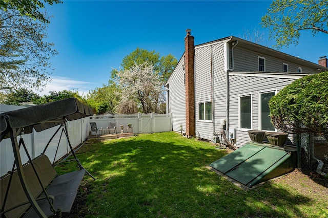 exterior space with a fenced backyard, a chimney, and a lawn