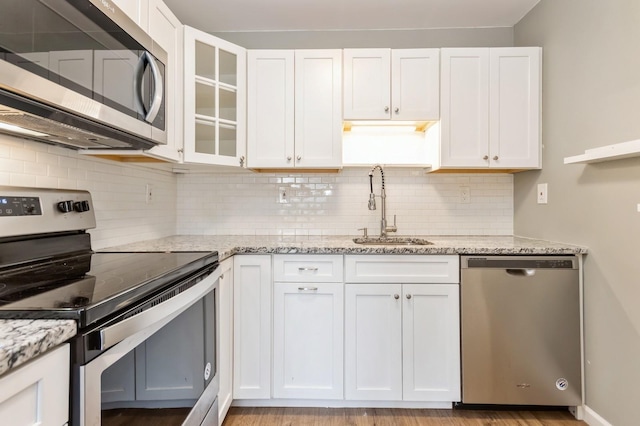 kitchen featuring a sink, white cabinetry, light stone countertops, and stainless steel appliances