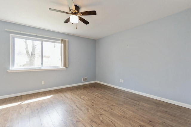 unfurnished room featuring baseboards, ceiling fan, visible vents, and wood finished floors