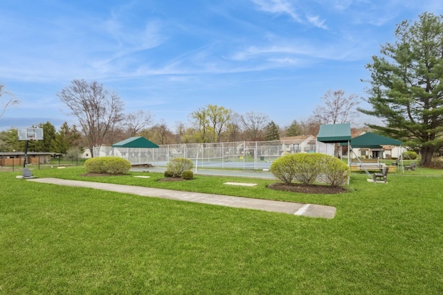 view of property's community with fence, a tennis court, and a yard