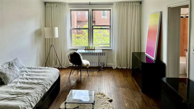 bedroom with radiator heating unit and dark wood-type flooring