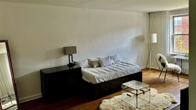 bedroom featuring baseboards, radiator, and dark wood-type flooring