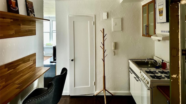 kitchen featuring a textured wall, a sink, extractor fan, dark wood finished floors, and white range with gas cooktop