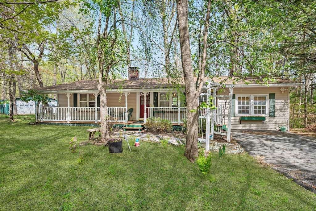 ranch-style house with covered porch, a chimney, and a front yard