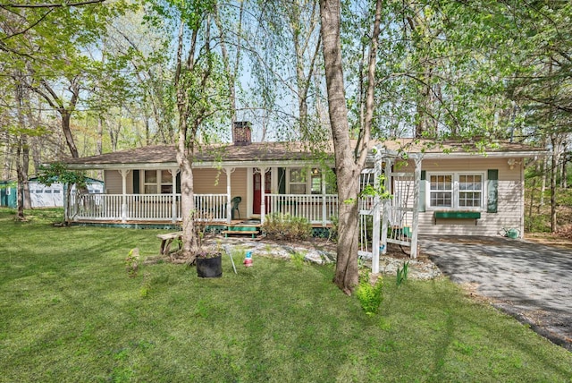 ranch-style house with covered porch, a chimney, and a front yard