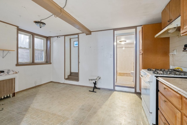 kitchen featuring white gas range, brown cabinetry, light countertops, radiator, and under cabinet range hood