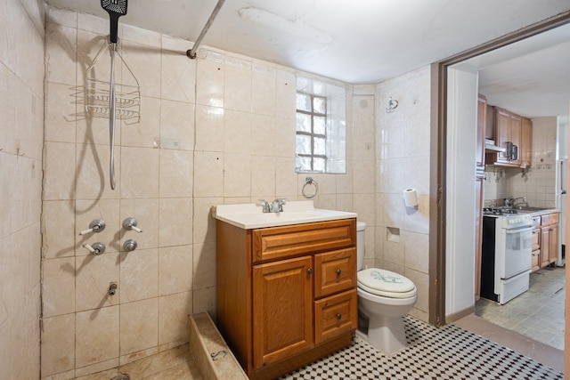 full bathroom with vanity, tile walls, a tile shower, and toilet
