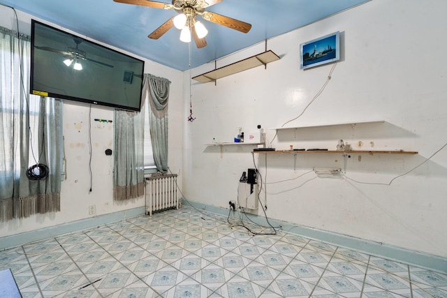 interior space featuring baseboards, radiator, ceiling fan, and light floors