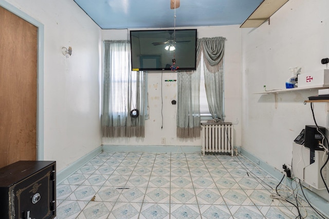 interior space with radiator heating unit, baseboards, a ceiling fan, and light floors