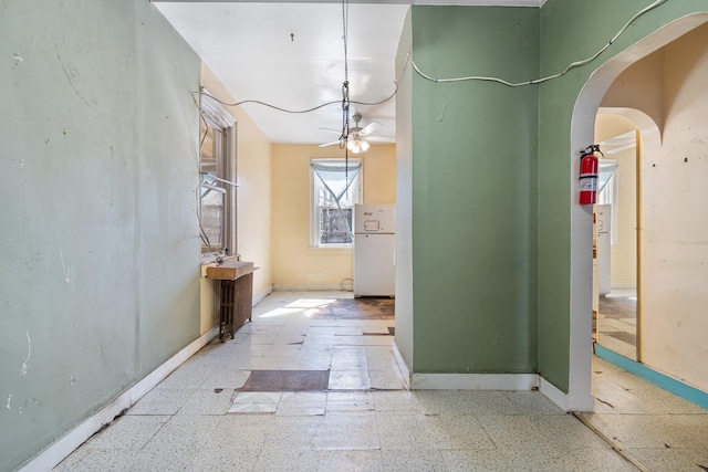 hallway featuring arched walkways and baseboards