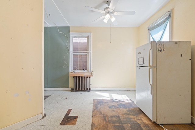 interior space with baseboards, freestanding refrigerator, radiator, and a wealth of natural light
