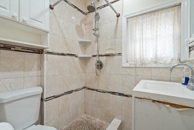 bathroom with toilet, a sink, tile walls, and tiled shower