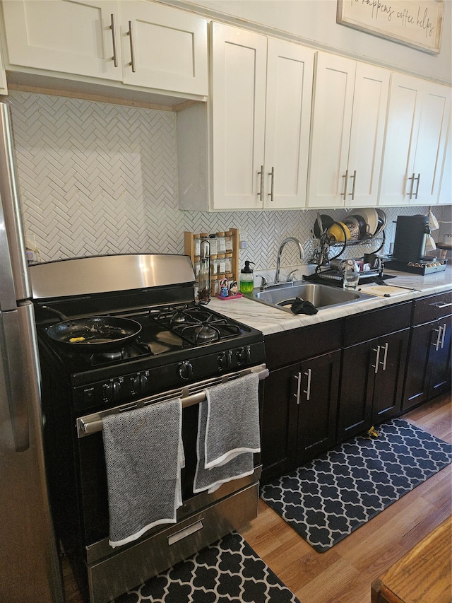 355 Ridgewood Ave, Brooklyn, NY 11208 - kitchen with stainless steel appliances, a sink, white cabinets, light countertops, and wood finished floors