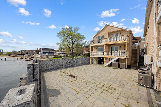 view of patio / terrace with stairs, central AC, a balcony, and a deck with water view