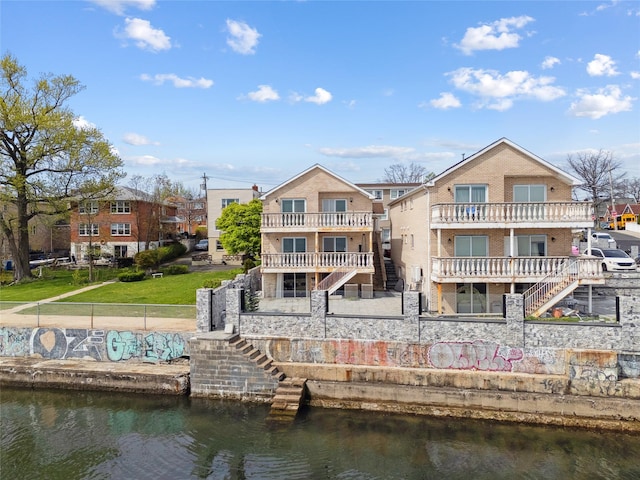 back of property featuring a fenced backyard, stairs, a water view, and brick siding