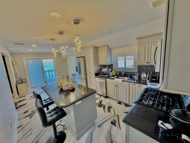 kitchen with stainless steel appliances, dark countertops, a sink, and tasteful backsplash