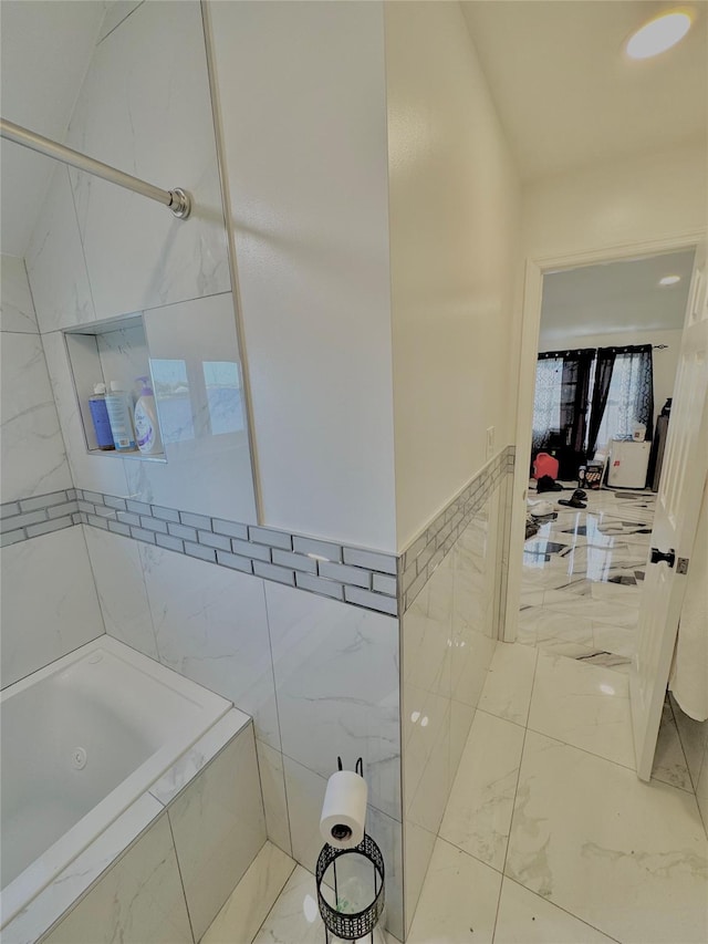 full bath featuring tile walls and marble finish floor